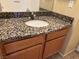 Bathroom vanity featuring granite countertop and wood cabinets with modern fixtures at 7300 Pirates Cove Rd # 2054, Las Vegas, NV 89145