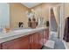 Bathroom with double sinks, large mirror, brown cabinets, and tiled floors at 7719 Villa Montara St, Las Vegas, NV 89123