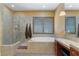 Bright bathroom with a tub, large glass shower, shutters, and makeup vanity at 7719 Villa Montara St, Las Vegas, NV 89123