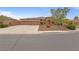 Spacious driveway leads to a tan single-story home with three-car garage and desert landscaping at 7719 Villa Montara St, Las Vegas, NV 89123