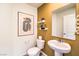 Stylish half bathroom with modern fixtures, a pedestal sink, decorative mirror, and neutral color palette at 794 Calm Crystal Ct # Lot 139, North Las Vegas, NV 89081