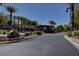 Community entrance to a neighborhood showcasing well-maintained landscaping, palm trees, and decorative boulders at 9713 Highridge Dr, Las Vegas, NV 89134