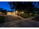 Exterior view of a home featuring a three-car garage, manicured lawn, mature trees, and inviting curb appeal under twilight at 9713 Highridge Dr, Las Vegas, NV 89134