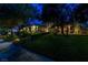 Twilight shot of a home with a well-maintained lawn, mature trees, and inviting landscape lighting creating a serene ambiance at 9713 Highridge Dr, Las Vegas, NV 89134