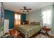 Cozy bedroom with dark wood floors, ceiling fan, and natural light from large windows at 9925 Turquoise Glass Ct, Las Vegas, NV 89178