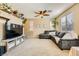 Inviting living room showcases a gray sectional, neutral carpet, shelving with plants, a large TV, and a ceiling fan at 10931 Sardinia Sands Dr, Las Vegas, NV 89141
