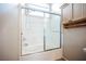Well-lit bathroom featuring a shower-over-tub with white tile and glass sliding doors at 1580 Wild Willey Way, Henderson, NV 89002