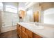 Bright bathroom with double vanity, large mirror, and shower over tub with glass doors at 1580 Wild Willey Way, Henderson, NV 89002