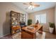 Home office with a large wooden desk, black rolling chair, built-in shelves and natural light at 1580 Wild Willey Way, Henderson, NV 89002