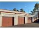 Exterior view of multiple attached garages, each with brown doors and brick accents at 1800 Edmond St # 218, Las Vegas, NV 89146