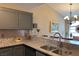 Close-up of kitchen with bar, gray cabinetry, granite counters, and stainless steel sink at 1800 Edmond St # 218, Las Vegas, NV 89146