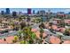 An aerial view captures a neighborhood with swimming pools, mature trees, and the iconic Las Vegas skyline in the background at 2704 Miraflores Ave, Las Vegas, NV 89102