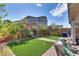 Serene backyard featuring artificial grass, manicured landscaping, patio seating, and a decorative water feature at 28 Verde Rosa Dr, Henderson, NV 89011