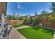 Backyard featuring artificial turf, decorative water feature, and mature landscaping, creating a private retreat at 28 Verde Rosa Dr, Henderson, NV 89011