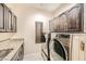 Well-lit laundry room with granite countertop, stainless steel washer and dryer, and cabinet storage at 3111 Lido Isle Ct, Las Vegas, NV 89117