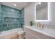 Stylish bathroom with blue tiled shower, bathtub, modern vanity, quartz countertop, and an illuminated mirror at 40 Laswell St, Henderson, NV 89015