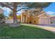 Exterior view of a yellow single-Gathering home featuring desert landscaping and a large shade tree at 4209 Glass Lantern Dr, North Las Vegas, NV 89032