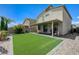 A backyard featuring artificial turf, a covered patio, and decorative desert landscaping at 4503 Meteora Ledge Ave, North Las Vegas, NV 89084