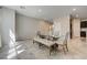 Bright dining area featuring neutral walls, tile floors, modern glass dining table with upholstered chairs and bench at 4503 Meteora Ledge Ave, North Las Vegas, NV 89084