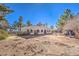 Large backyard featuring a white stucco home with arched openings, set among mature trees and natural vegetation at 5715 Gilbert Ln, Las Vegas, NV 89130