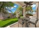A covered patio with outdoor seating overlooks the well manicured lawn at 575 Dusty Palms Ln, Henderson, NV 89052