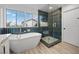 Modern bathroom featuring a soaking tub, walk-in shower with designer tile, and natural light from large windows at 575 Dusty Palms Ln, Henderson, NV 89052