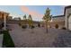 A spacious backyard featuring gravel landscaping, pavers, and young trees at 5865 Alice Landing Ct, Las Vegas, NV 89149