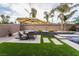 Landscaped backyard featuring artificial grass, a dining area and retaining wall by the pool at 5865 Alice Landing Ct, Las Vegas, NV 89149