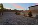 An open backyard with pavers, gravel landscaping, young trees, and privacy walls at 5865 Alice Landing Ct, Las Vegas, NV 89149