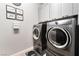 Modern laundry room with gray cabinets, framed decor, a stacked washer-dryer, and attractive floor mat at 5865 Alice Landing Ct, Las Vegas, NV 89149