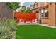 A backyard with green artifical turf and a modern wooden fence with outdoor seating at 617 Apricot Rose Pl, Las Vegas, NV 89138