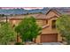 Attractive tan two-story home with a tiled roof, front balcony, mature landscaping, and mountain views at 617 Apricot Rose Pl, Las Vegas, NV 89138