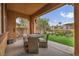 A covered patio with a table and chairs and a view of the backyard's artifical turf at 617 Apricot Rose Pl, Las Vegas, NV 89138