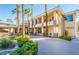Inviting two-story building with tan exterior, balconies, and palm trees in a well-maintained landscaped complex at 7189 S Durango Dr # 203, Las Vegas, NV 89113