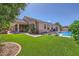 Lush backyard features a pool, green lawn, covered patio, and mature trees at 7418 Lawrence Powers Ct, Las Vegas, NV 89129