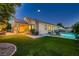 Beautifully landscaped backyard with a pool, patio, and lush green lawn at dusk at 7418 Lawrence Powers Ct, Las Vegas, NV 89129