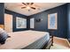 Spacious bedroom featuring three windows, carpet flooring, blue walls, and a ceiling fan at 7418 Lawrence Powers Ct, Las Vegas, NV 89129