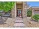 Close-up of the home's entrance featuring stone accents, a charming porch swing, and a well-maintained brick walkway at 7418 Lawrence Powers Ct, Las Vegas, NV 89129