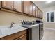 Well-lit laundry room features front-load washer/dryer, utility sink, and ample cabinet storage at 7418 Lawrence Powers Ct, Las Vegas, NV 89129