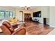 Living room featuring hardwood flooring, plantation shutters, and a large entertainment center at 7418 Lawrence Powers Ct, Las Vegas, NV 89129