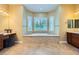 This is a bright main bathroom with an elegant tub, double vanities, and travertine floors at 7418 Lawrence Powers Ct, Las Vegas, NV 89129