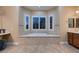 Relax in this elegant main bathroom with travertine floors, double vanities, and a soaking tub at 7418 Lawrence Powers Ct, Las Vegas, NV 89129