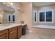 This bright main bathroom has travertine floors, double vanities, and a soaking tub at 7418 Lawrence Powers Ct, Las Vegas, NV 89129