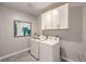 Functional laundry room equipped with modern appliances, overhead storage, and tiled floors at 7705 Serenity Bay Ln # Lot 57, North Las Vegas, NV 89084