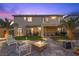 Outdoor living space featuring a manicured lawn, fire pit, palm trees and second story balcony at dusk at 8208 Fritzen Ave, Las Vegas, NV 89131