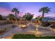 Outdoor living space with hot tub, fire pit, gazebo, palm trees and manicured lawn at dusk at 8208 Fritzen Ave, Las Vegas, NV 89131