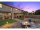 Backyard at dusk with a fire pit, patio, lighting, upper balcony and small lawn at 8208 Fritzen Ave, Las Vegas, NV 89131