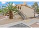 Exterior view of a condo building with a black staircase leading to the 2nd story and a large palm tree at 1112 Observation Dr # 201, Las Vegas, NV 89128