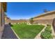 Backyard with synthetic grass, desert landscaping, and secure brick wall creating a private outdoor space at 12546 Mosticone Way, Las Vegas, NV 89141