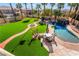 Expansive backyard featuring a luxurious pool with waterfall feature and lush artificial turf at 1407 Fields St, Las Vegas, NV 89142